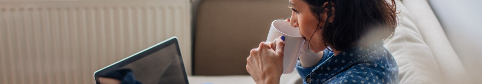 woman sitting on her couch drinking coffee