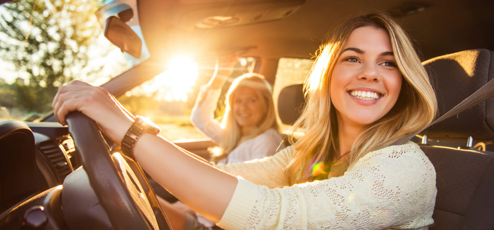 Young woman behind the wheel of a car with a passenger 